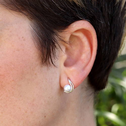 Perle naturelle sur double tige courbée en or blanc fixée sur l'oreille d'une femme.