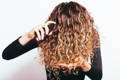 woman with curly hair applying leave in conditioner