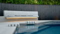 Curved outdoor bench with integrated warm LED strip lighting overlooking a backyard swimming pool.