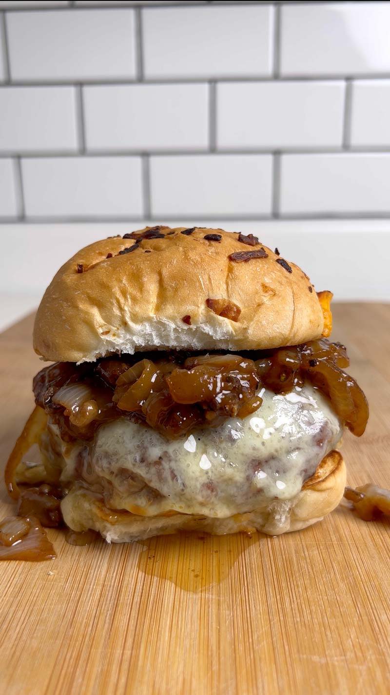 BetterFed Beef Bone Marrow French Onion Burger. Half-pound 1/2 pound burger patty served on a toasted bun with caramelized onions, melted cheese, and smoked bone marrow.