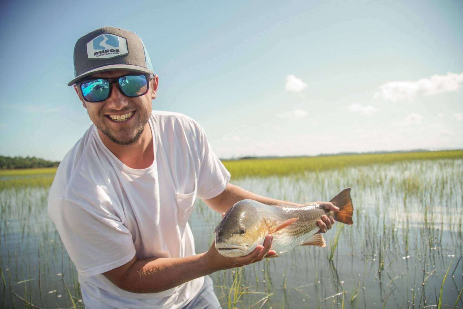 A fisherman holds a fresh-caught red drum fish, seen easier without glare.