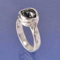 A memorial ring with cremated ashes in a black glass bead, set on a ring