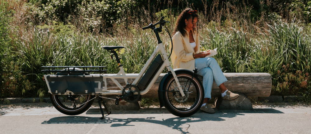 Woman reading a book next to Specialized Globe Haul electric cargo bike