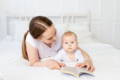 Mother reading a book with her baby during calm bonding time on a bed