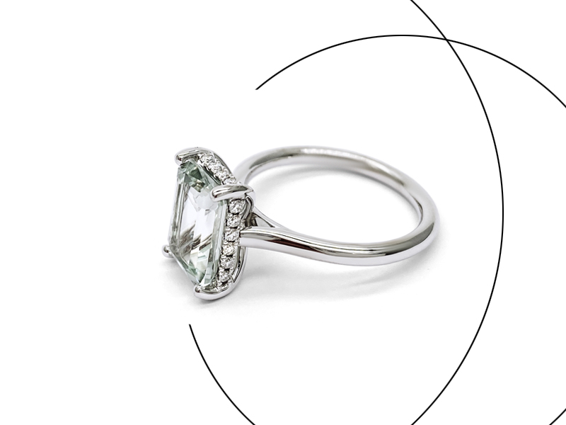 Large princess diamond mounted on a white gold engagement ring with small diamonds on the outline of the main stone