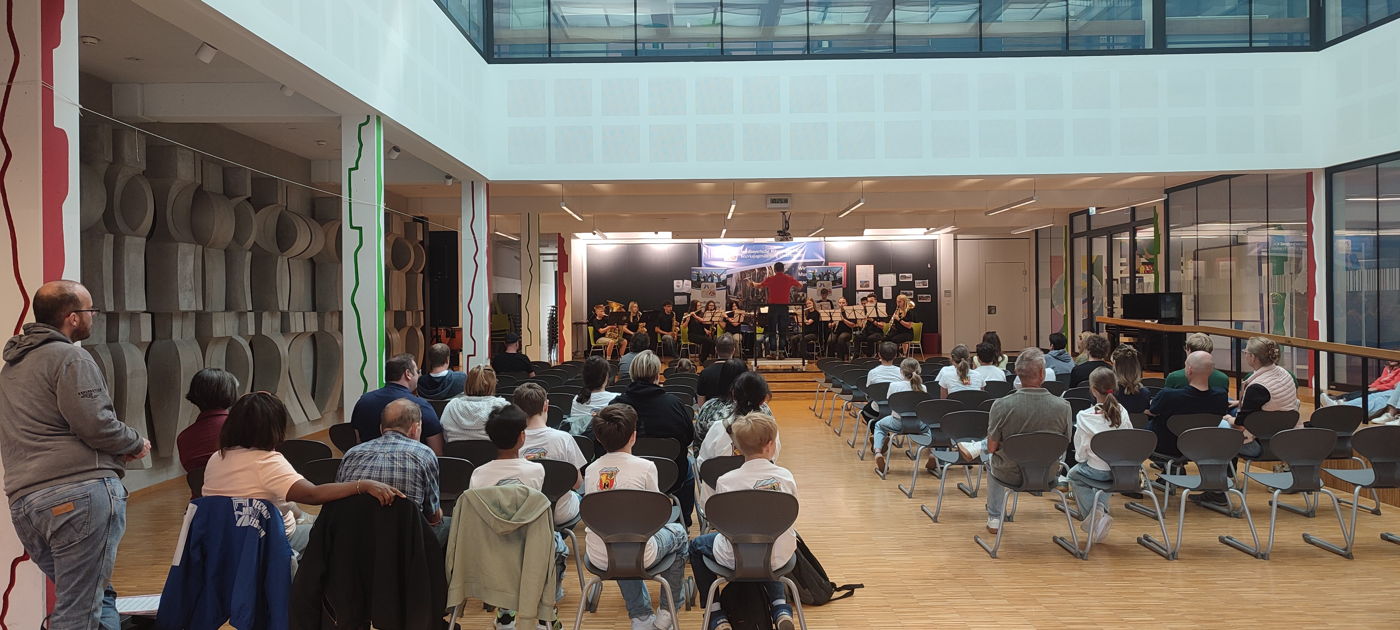 Auf einer Bühne vor Publikum musiziert ein Orchester. 