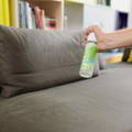 Watch as a man sprays Yokuu's natural cleaning spray on a brown couch in a beautifully designed modern home.