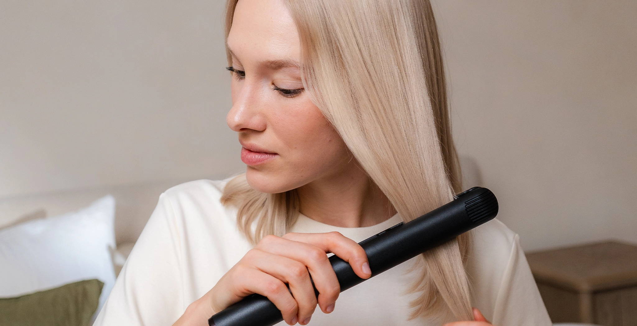 blonde Frau, die sich die Haare glättet