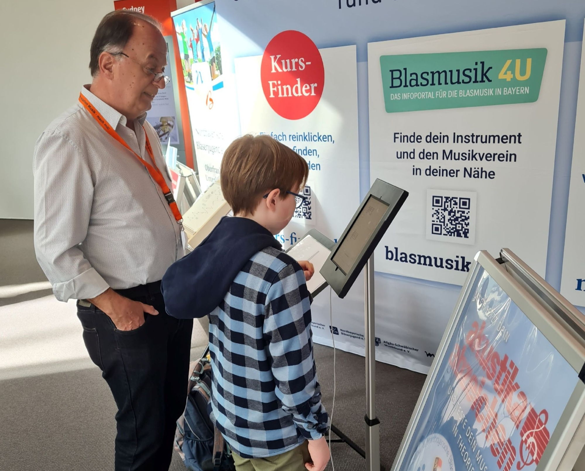 Ein Mann und ein Junge stehen gemeinsam vor einem iPad und lösen digital ein Quiz. 