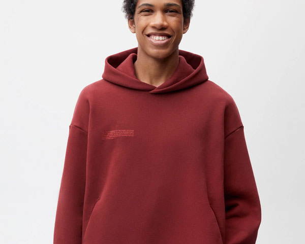 Man wearing burgundy organic cotton and recycled cotton hoodie from sustainable UK men's clothing brand Pangaia