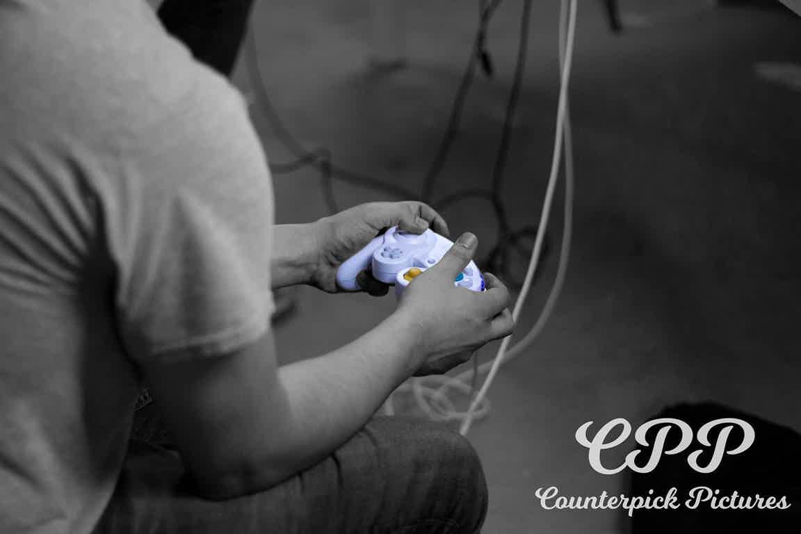 Desaturated torso-downward side-shot of player holding fully saturated controller in their tournament match