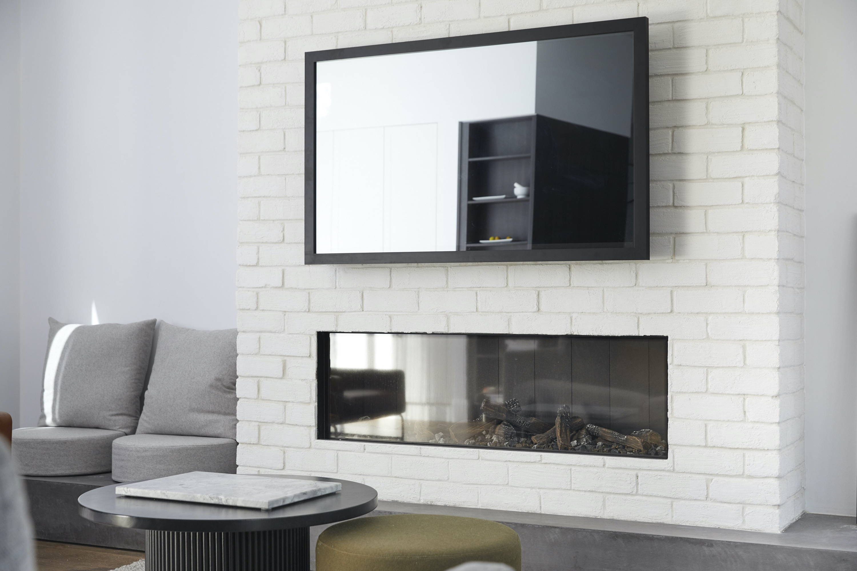 A TV-Mirror hanging on the wall of a coastal, elegant bedroom setting 