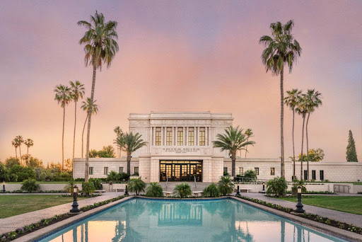 The Mesa Temple with an orange and purple sky. The blue reflection pool stretches out toward the viewer.