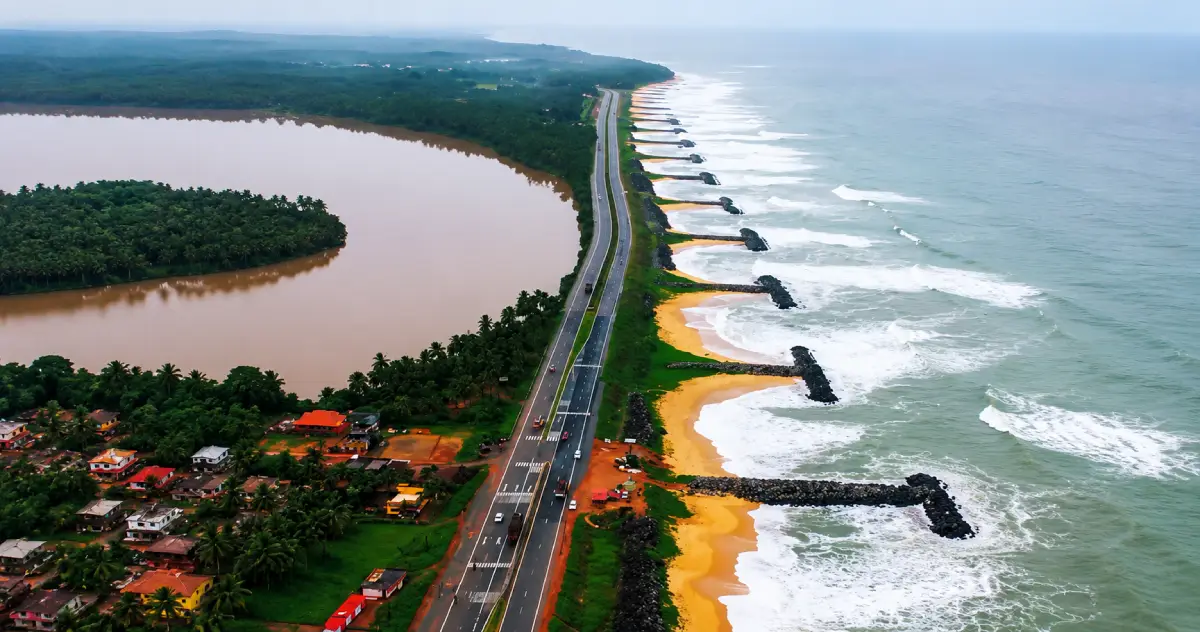 Coastal highway in Karnataka with vehicles travelling near the sea