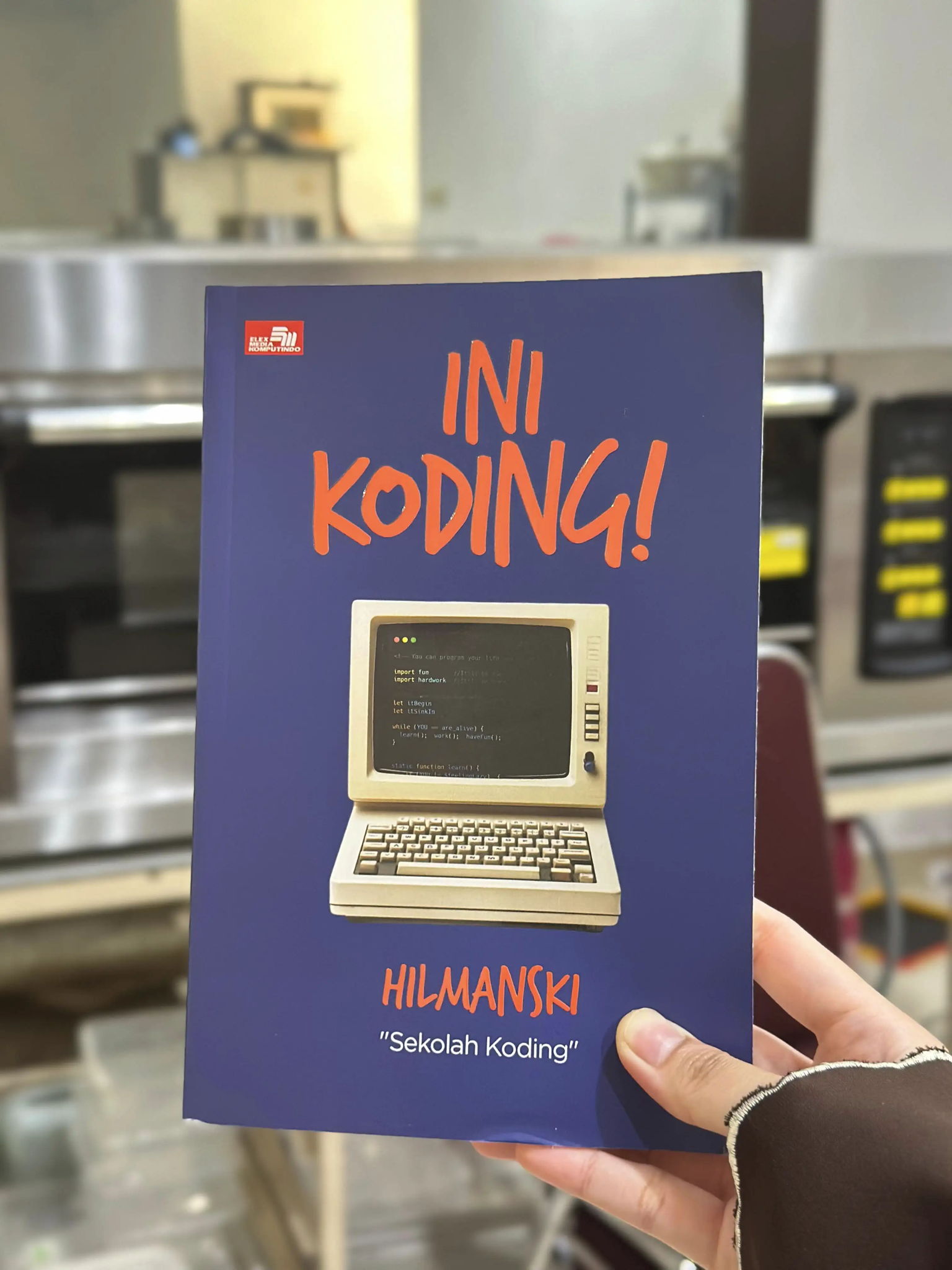 Foto buku pemrograman dipegang