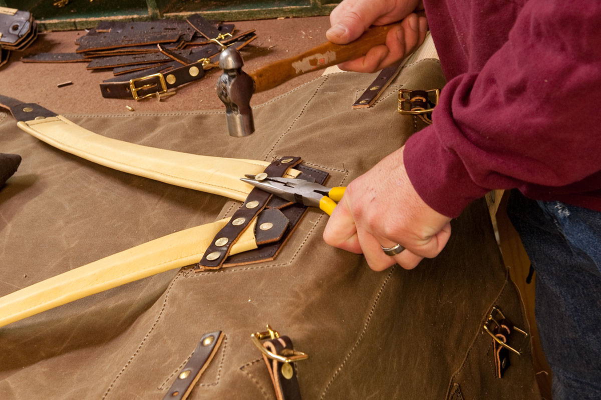 tack being hammered into the straps of a pack