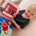 Little girl looking at camera and smiling while holding the Montessori Story Book in her lap. 