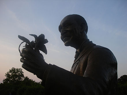 Silhouette of a statue of George holding a flower.