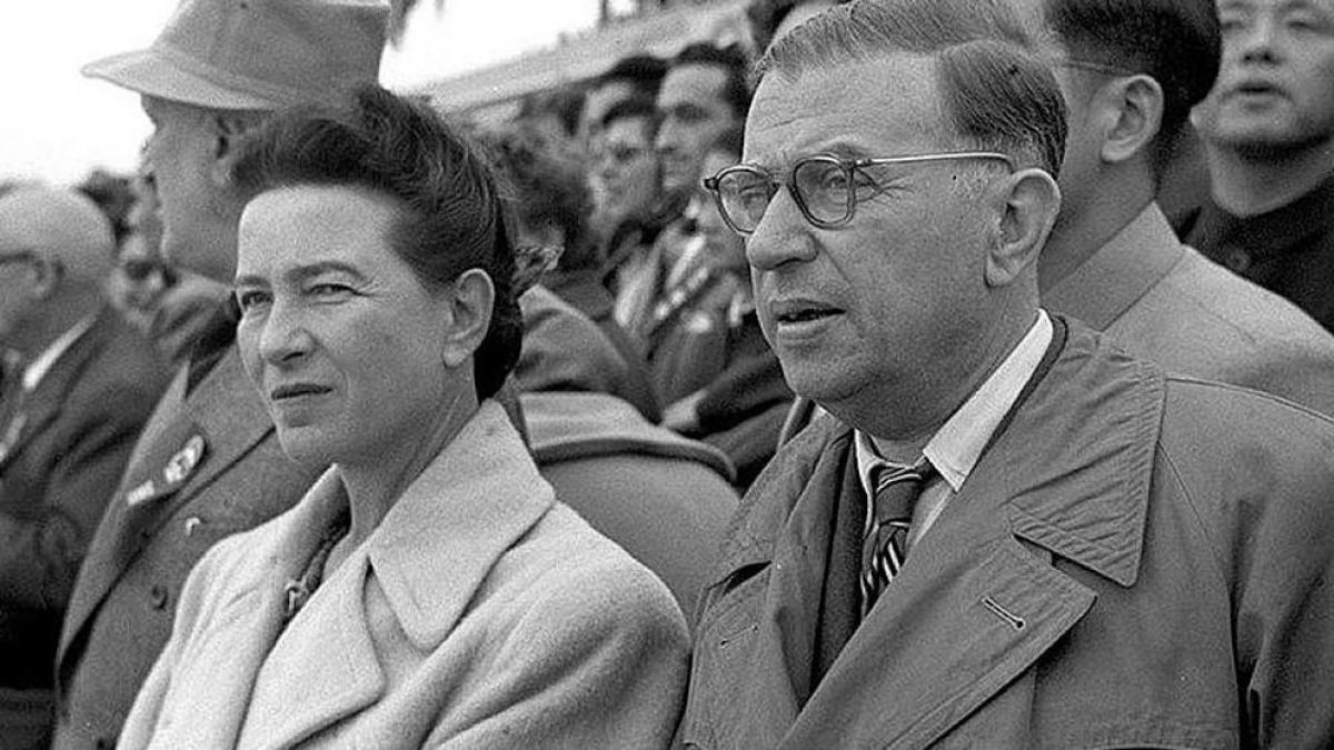 Simone and Jean-Paul Sartre sitting in their seats at a stadium with other attendees.