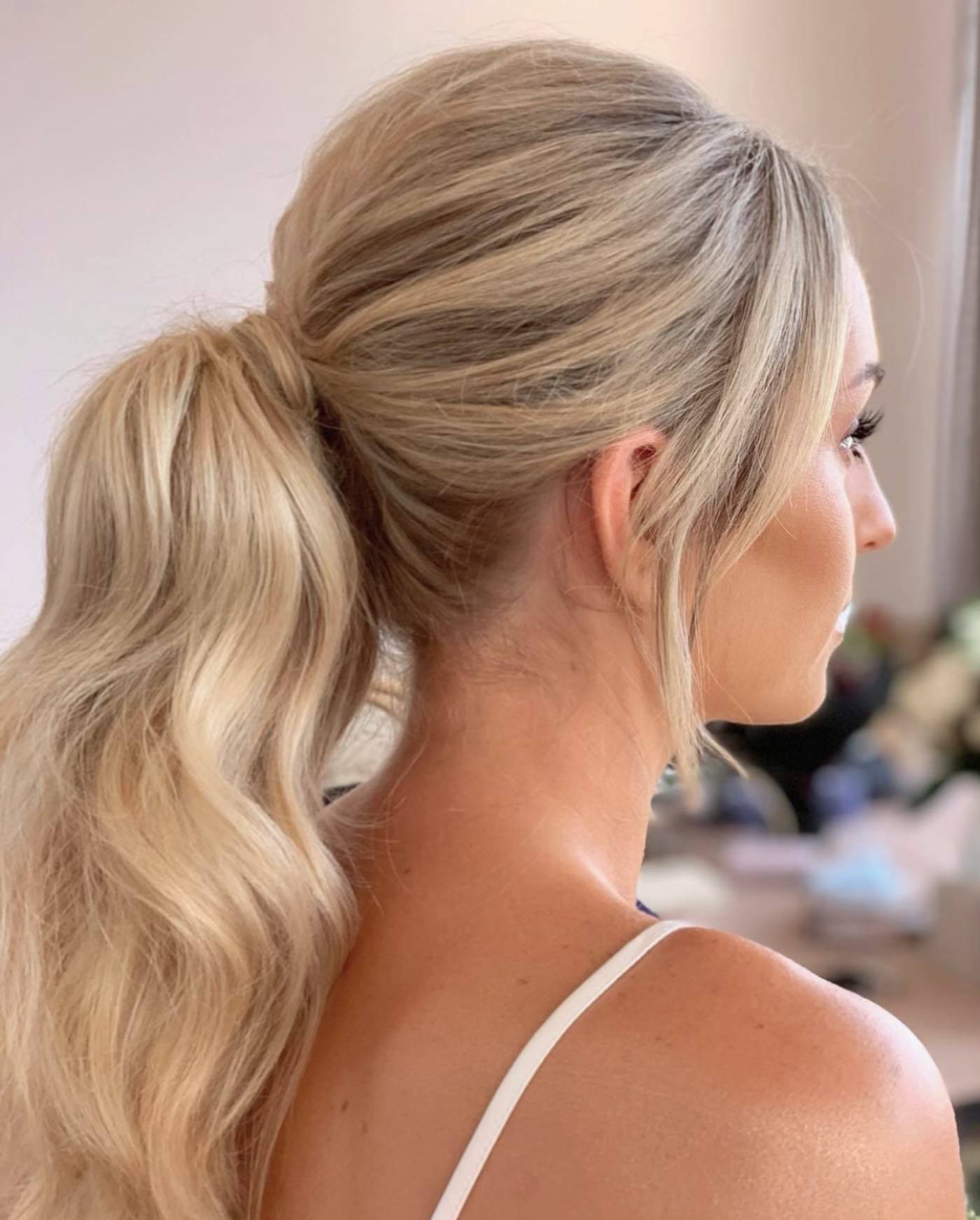 Blonde haired bride wearing hair extensions in a ponytail for her wedding.