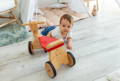 Baby crawling beside a wooden baby balance bike in a Montessori-style playroom