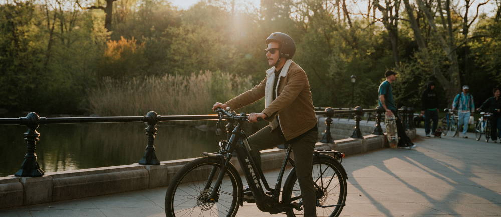 A man riding a Trek Allant electric bike next to a pond