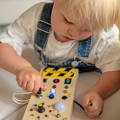 Little boy playing with Montessori Wooden Sensory Board in the back of the car while traveling.