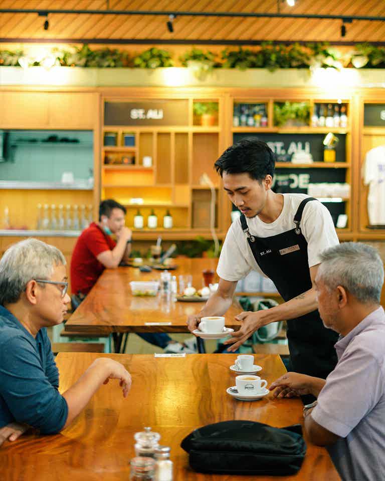 Barista serving two people their coffees 