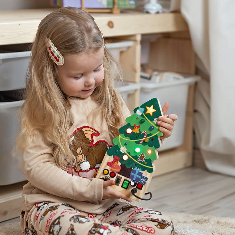 Little girl smiling while holding the Montessori Christmas Switch Board.