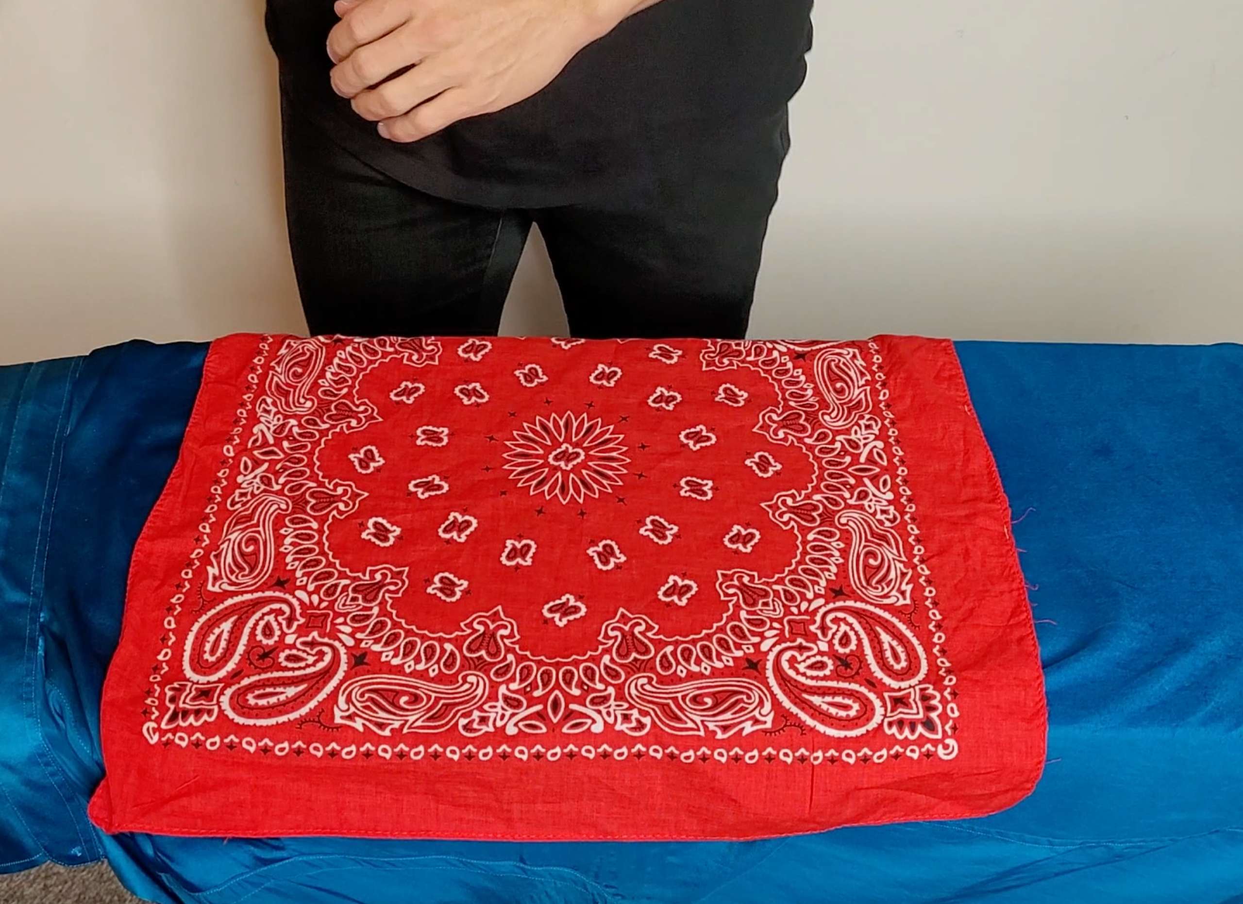 photo of a red bandana press cloth laid overtop of a satin shirt