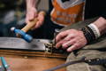 a man hammering part of a buckle on the wing of a pack