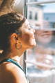 woman looking at the window to catch sun rays  for a youthful skin
