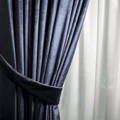 blue curtain with a tie in front of a thinner white curtain in the back