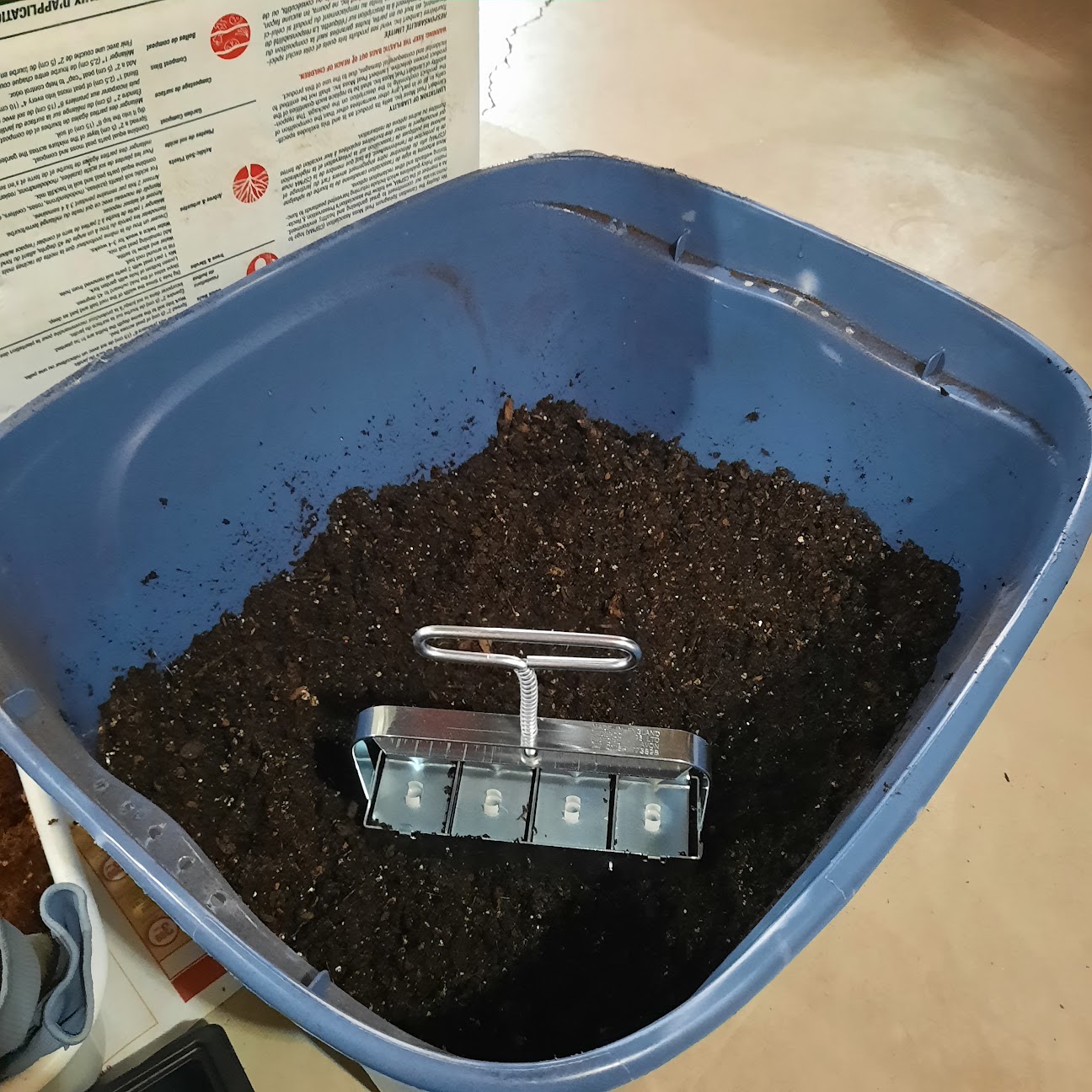Soil blocker tool in a tub filled with blocker soil mix