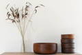 vintage wooden salad bowl set on shelf with vase of grass