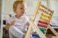 Little girl learning to count on a wooden abacus.