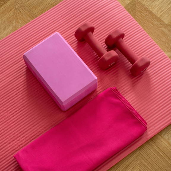 A set of pink workout weights on a yoga mat.