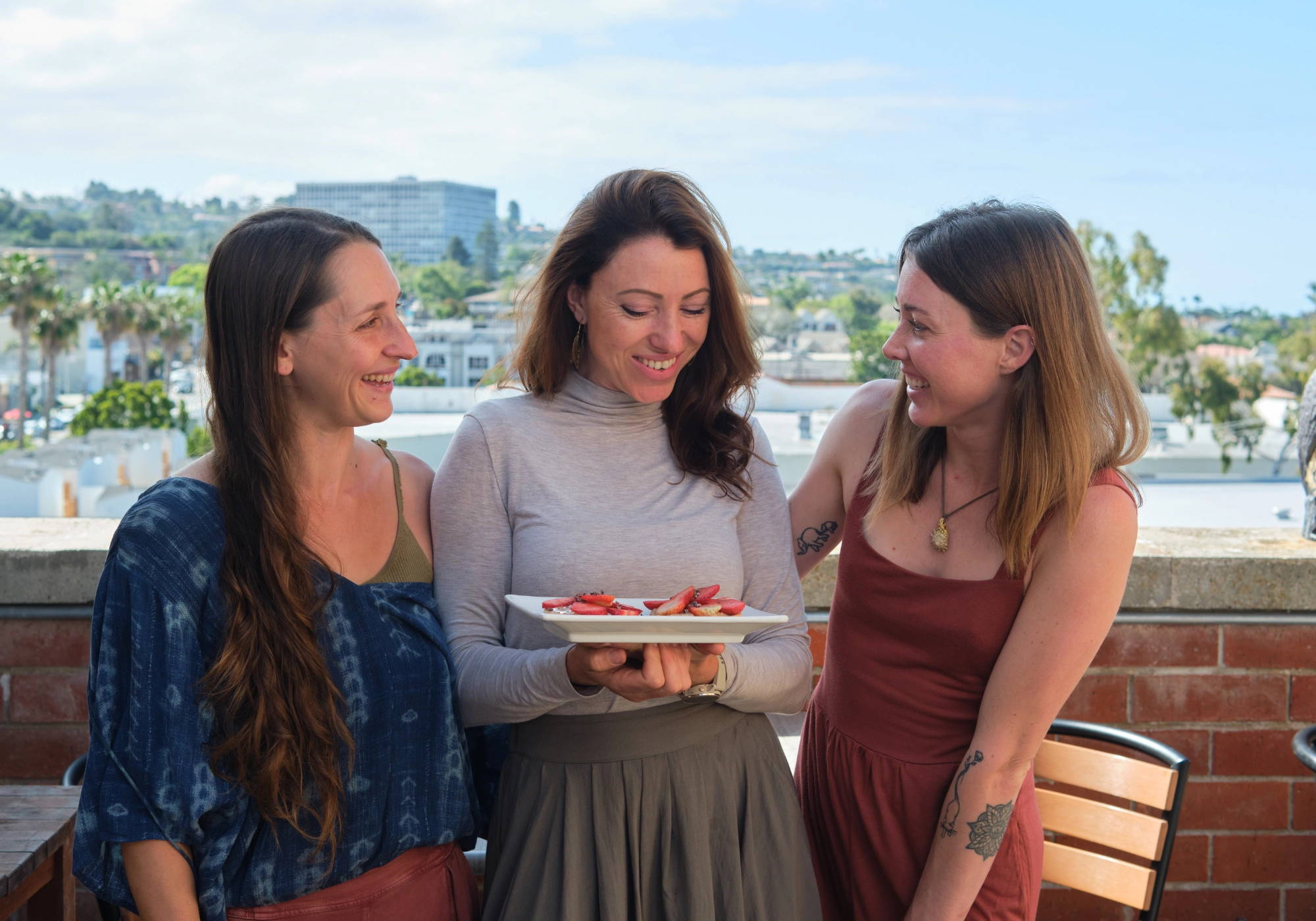 Three women smiling while enjoying PACHA sprouted buckwheat bread together.