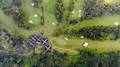 Overlooking view of a luxury golf clubhouse with a symmetrical design surrounded by green fairways and trees.
