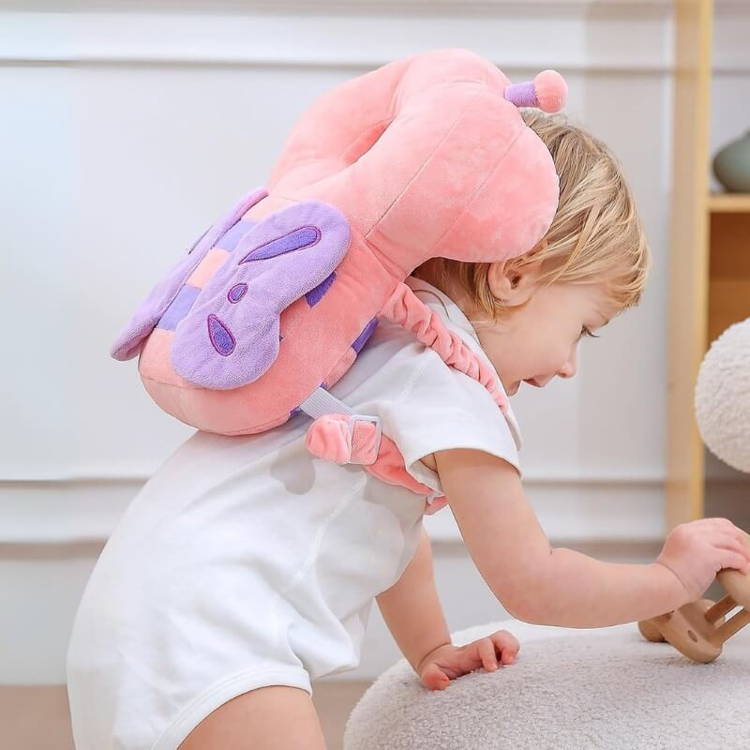 Une petite fille joue avec un hochet en bois tout en portant son sac à dos protecteur en forme de coussin Montessori Ange Gardien.