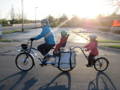 Cycliste à vélo cargo avec deux enfants passant par la route