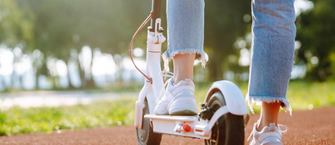 Vrouwelijke voeten op een elektrische scooter.