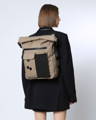Woman wearing a beige recycled backpack with roll top, from Cologne based sustainable bags and luggage brand, Pinq Pong.