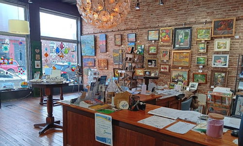 Cozy art gallery with framed artworks, warm wooden interiors, natural light, and an inviting atmosphere for creativity and community.