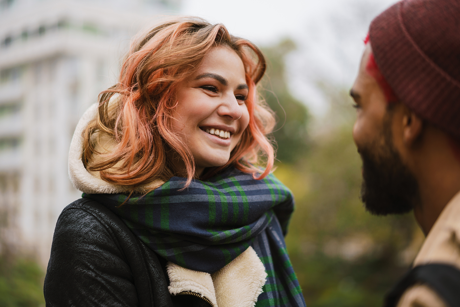Couple looking at each other. Both smiling and wearing winter clothing.