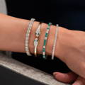 Woman with a set of yellow gold diamond and emerald bracelets on her wrist