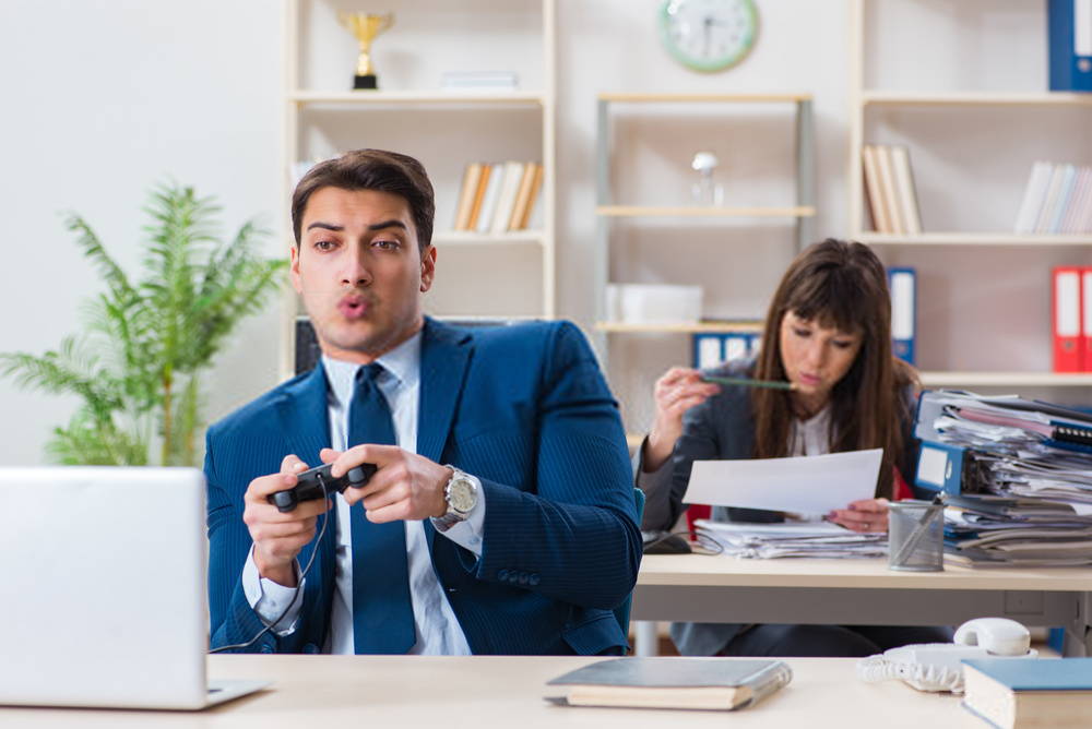 Man in suit playing video games at his work desk 