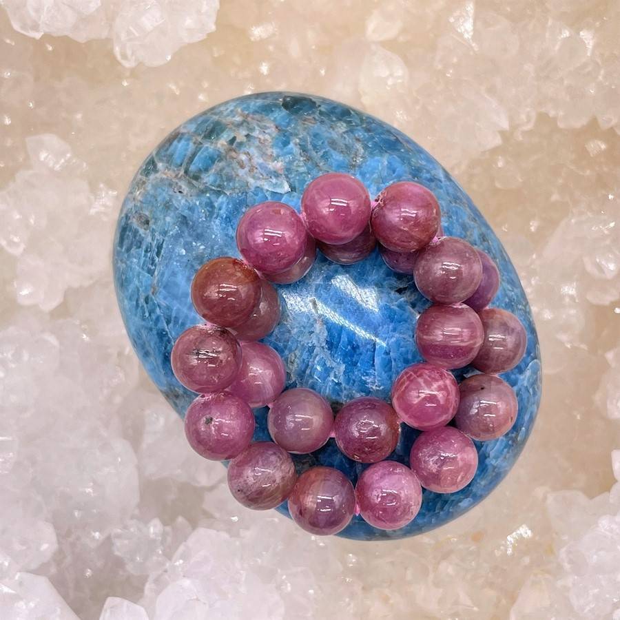 un bracelet en pierres naturelles de rubis sur un galet en apatite bleue sur une géode de quartz pour la purification en lithothérapie