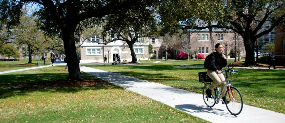 Student on electric bike riding on sidewalk on college campus