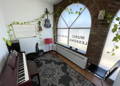 An image of a classroom with a digital piano, guitars hanging on the wall, and a large window inside South Windsor School of Music.